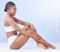 I have a loving relationship with my body. a young woman touching her legs while sitting against a blue background.