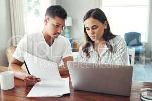 Checking the figures. a young couple using a laptop to their household budget in the living room at home.