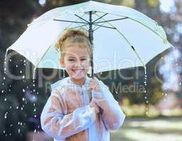 This is the best kind of weather. a little girl playfully standing in the rain holding her umbrella.