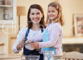 Baking is a team sport. a young mother helping her daughter sift flour into a bowl.