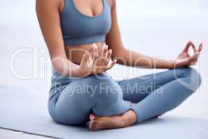 Its a matter of the mind. an unrecognizable young woman meditating while practicing yoga on the beach.