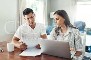 Going over their finances. a young couple using a laptop to their household budget in the living room at home.