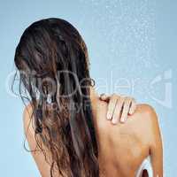 Top to toe freshness. Studio shot of an attractive young woman taking a shower against a blue background.