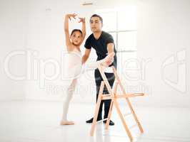 Ballet builds confidence and self esteem. a ballet teacher assisting a student with her position in a dance studio.
