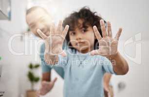 All the germs are gone now. Portrait of a little boy holding up his soapy hands while standing in a bathroom with his father at home.