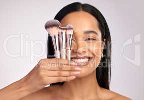 A brush for every occasion. Studio portrait of an attractive young woman posing with a variety of makeup brushes against a pink background.