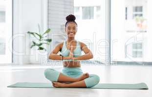 Its important to find inner peace. Full length shot of an attractive young woman sitting alone with her legs crossed and meditating in the studio.