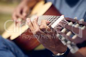 Play to the rhythm of your heartbeat. an unrecognisable man playing the guitar outside at college.