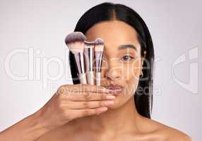 Take your pick. Studio portrait of an attractive young woman posing with a variety of makeup brushes against a pink background.