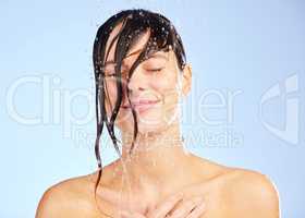 Washing away the day. a young woman washing her hair in the shower against a blue background.