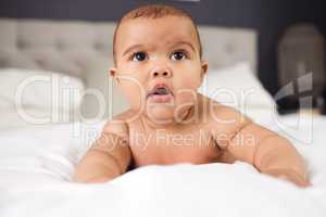 Pure happiness is found in nothing but in a innocent baby. an adorable baby boy on the bed at home.