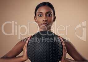 Its time to tone up those arms. an attractive young woman standing alone in the studio and holding a medicine ball while working out.