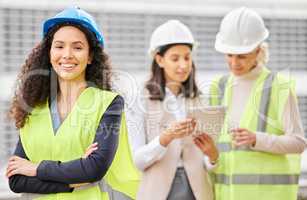 Management is on the job. Cropped portrait of an attractive young female engineer standing with her arms folded with her colleagues in the background on a construction site.