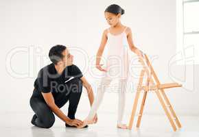 Hold onto the chair for some balance. a ballet teacher assisting a student with her position in a dance studio.