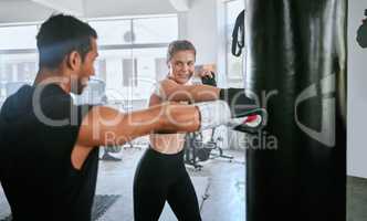 Active and fit man and woman boxing, exercising and training together for fitness at the gym. Young, sporty and serious couple doing a routine cardio workout and working out at a sports center