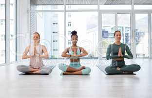 Start your day off with the right vibe. Full length shot of a diverse group of women sitting together in a yoga studio and meditating.