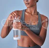 Hydration and health go hand in hand. Studio shot of a fit young woman drinking bottled water against a grey background.