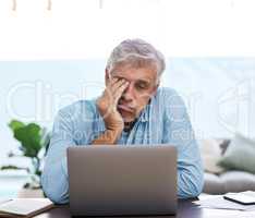 I cant keep doing this. a mature man sitting alone and feeling stressed while using his laptop to work from home.