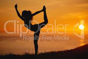 Life is all about balance. Full length shot of an unrecognizable and athletic young woman practicing yoga outside at sunset.