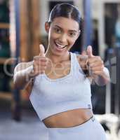 Exercise will be a great benefit towards your life. Portrait of a sporty young woman showing thumbs up in a gym.