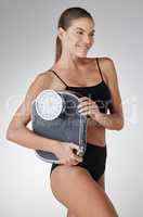 Tomorrows body is todays diet. Studio shot of an attractive and fit young woman holding a scale against a grey background.