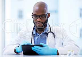 It seems we need to do more tests. a handsome young doctor sitting alone in his clinic and using a digital tablet.