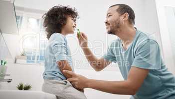 Your little teeth are so precious. a father brushing his little sons teeth in the bathroom at home.