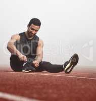 Made for endurance and performance. a young male athlete tying his shoe laces before a race.