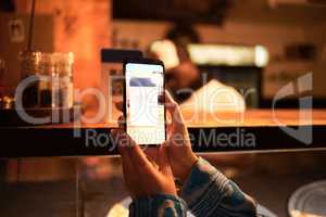 Person with phone camera scanning QR bar code for online menu at a modern restaurant, shop or cafe at night. Hand of a woman taking photo scan for website information using modern technology