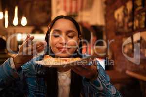 Hungry woman with delicious pizza, food or consumables at a bar, restaurant or diner at night. One happy and casual girl, foodie or tourist enjoying a dinner meal at a local trendy location