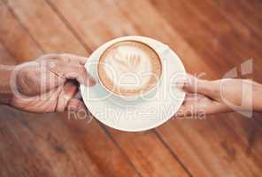 Service, customer and serving coffee to a cafe client and giving a cup of hot and fresh drink with milk foam at coffeeshop. Closeup of hands holding cappuccino with beautiful cream of latte art