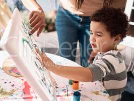 Messy play is important to every childs development. a little boy painting on a canvas with his mother.