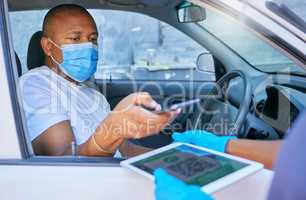 Covid drive thru checkpoint man scanning QR code on a tablet with his phone traveling in a car. Man driving wearing a face mask at a coronavirus screening service using technology to send details