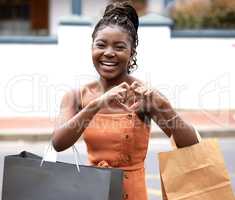 It is instant gratification, a quick fix. a young woman walking through the city with shopping bags and make a heart sign with her hands.