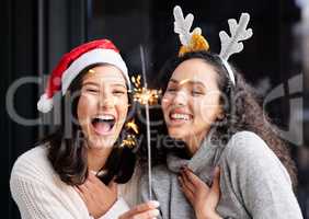 Christmas waves a magic wand over this world. two friends using a sparkle stick ay home.