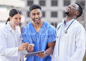 Laughter can cure almost everything. a group of doctors using a digital tablet against a city background.