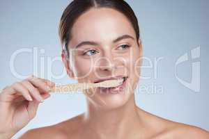 Thoughts on dental hygiene. Studio shot of an attractive young woman brushing her teeth against a grey background.