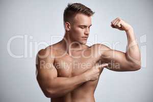 I accepted the challenge and look what I got. Studio shot of a muscular young man flexing his arm against a grey background.
