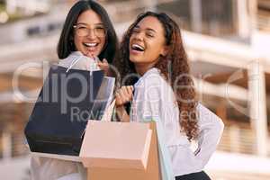 Earn dollars to spend dollars. two attractive young women standing outside together and bonding while shopping in the city.
