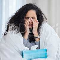 I dont know how not to get the flu. an uncomfortable looking young woman blowing her nose while lying in bed at home.