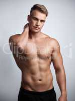 You can stare all you want. Studio portrait of a muscular young man posing against a grey background.