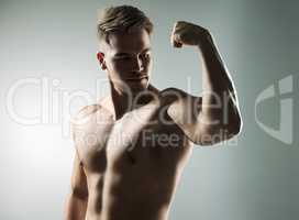 Do daily what others do occasionally. Studio shot of a muscular young man flexing his arm against a grey background.