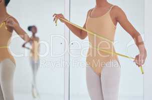 Just a few more inches to go. an unrecognizable ballet dancer measuring her waist during a rehearsal.