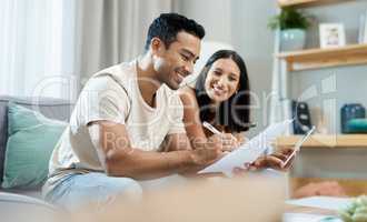 Were doing so well with our finances. a young couple sitting together in their living room at home and calculating their finances.