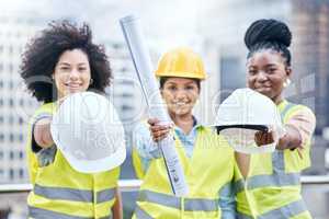The site managers are here to do their inspection. Portrait of a group of confident young businesswomen holding blueprints and hardhats while working at a construction site.