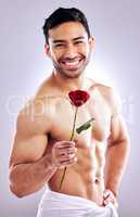 I hope youll accept this rose. Studio shot of a handsome young man posing with a red rose.