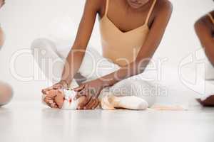 No pain , no gain. an unrecognizable ballet dancer tying on her pointe shoes.