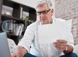 Where did those come from. a mature man checking some paperwork on the sofa at home.