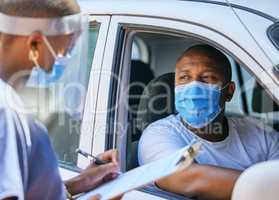 Test, questions and screening at a covid drive thru checkpoint. A man traveling in a car talking to a healthcare professional writing his coronavirus details while wearing a face mask