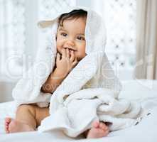 Im enjoying my daily pamper session. an adorable baby covered in a towel after bath time.